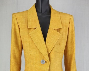 May include: A mustard yellow linen blazer and skirt suit with three white buttons on the front of the blazer.