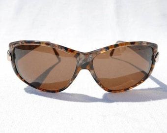 May include: Tortoiseshell sunglasses with brown lenses. The sunglasses have a sleek, modern design.