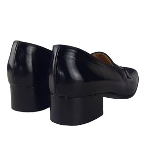 May include: A pair of black leather loafers with a low block heel. The shoes have a pointed toe and a slip-on design.
