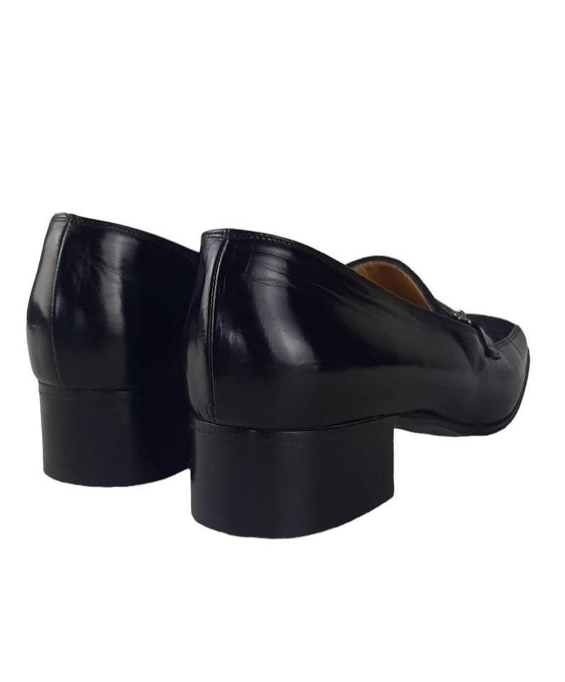 May include: A pair of black leather loafers with a low block heel. The shoes have a pointed toe and a slip-on design.