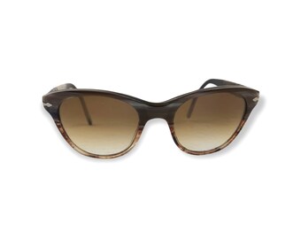 May include: Brown tortoiseshell cat-eye sunglasses with gradient brown lenses.