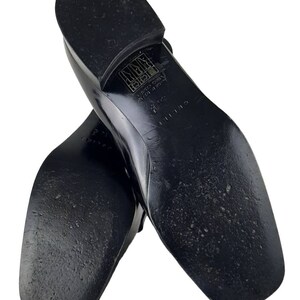 May include: Black leather loafers with a square toe and a rubber sole. The sole has the text "CELINE" and "MADE IN ITALY" printed on it.