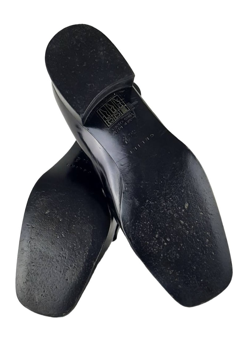 May include: Black leather loafers with a square toe and a rubber sole. The sole has the text "CELINE" and "MADE IN ITALY" printed on it.