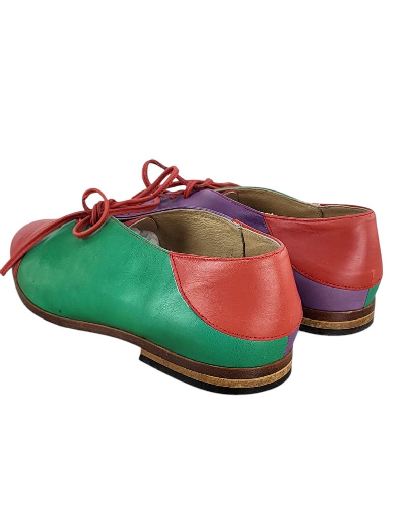 以下が含まれることがあります： 緑、赤、紫の革製のレースアップシューズのペア。シューズは丸みを帯びたつま先と低いヒールを持っています。