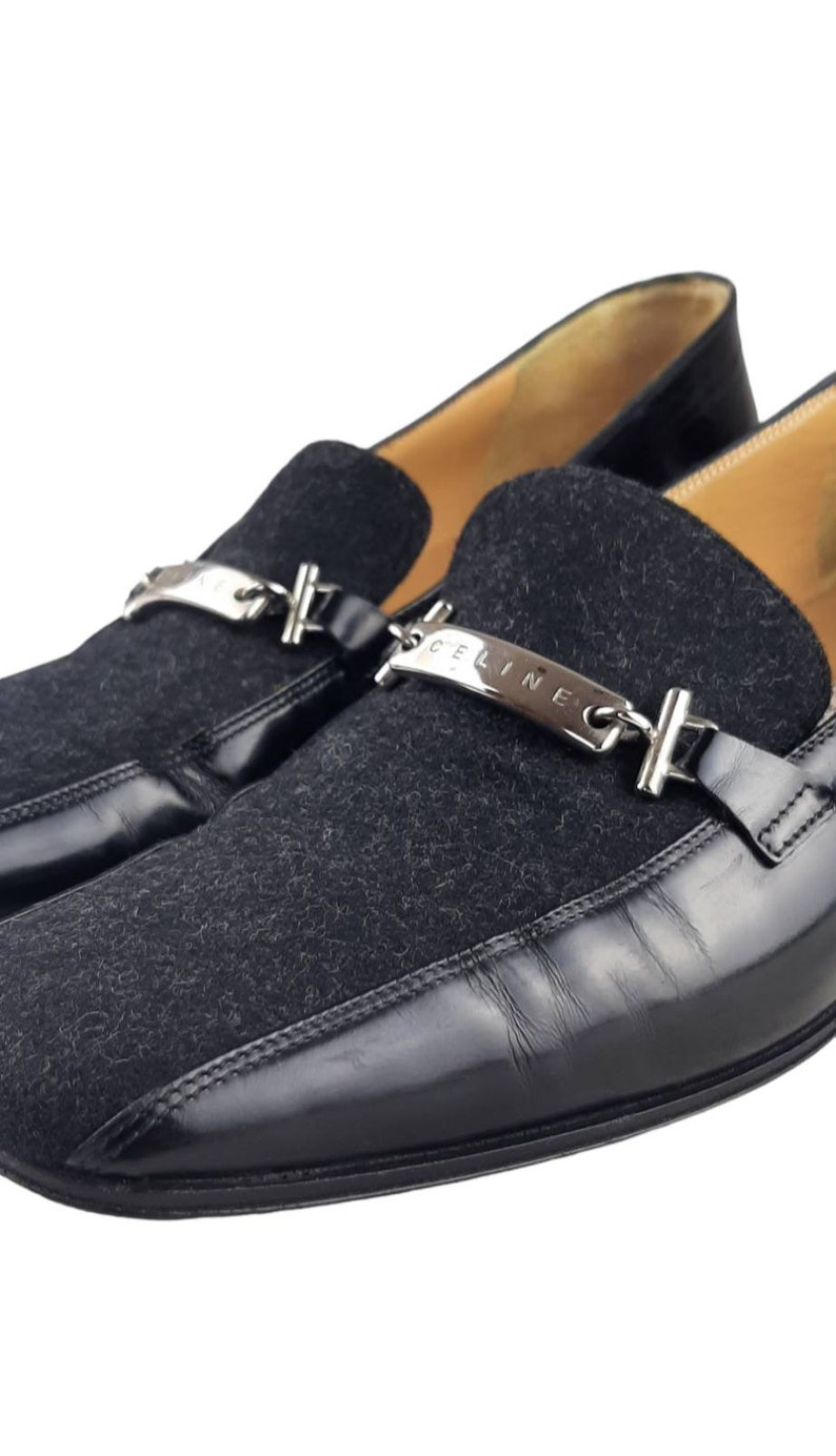 May include: Black leather and suede loafers with a silver chain and "CELINE" nameplate detail.