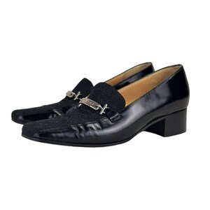 May include: Black leather heeled loafers with a silver buckle and a black fabric toe. The buckle has the word "CELINE" engraved on it.