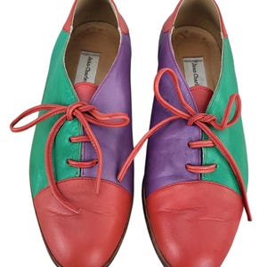 以下が含まれることがあります： ブランド名「Jean-Charles」が内側に書かれた、赤、緑、紫の革製のレースアップシューズのペアです。