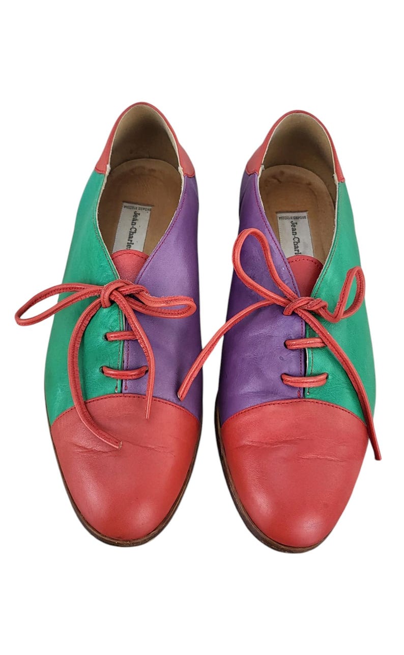 以下が含まれることがあります： ブランド名「Jean-Charles」が内側に書かれた、赤、緑、紫の革製のレースアップシューズのペアです。