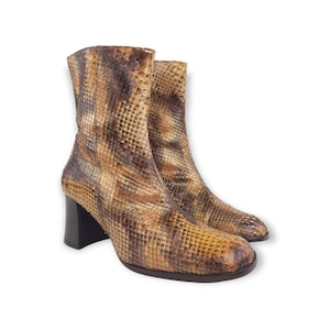 Peut inclure: Une paire de bottines à cheville en cuir de serpent brun et beige avec un talon bloc.