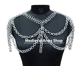 May include: Silver chainmaille shoulder armour necklace with a decorative design. The necklace is displayed on a black mannequin. The text "Medieya Arms Shop" is visible on the necklace.