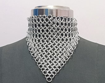 May include: A silver chainmail choker necklace on a black mannequin bust. The necklace is made of small, interlocking metal rings.