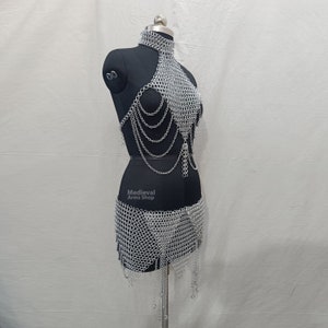 May include: A silver chainmail top and skirt set. The top is a halter style with a chainmail design and the skirt is a short, flowing style.