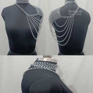 May include: Silver chainmaille shoulder armor with a matching choker necklace. The armor is made of interlocking metal rings and has a flowing, draped design.  Medieval Armor Shop.