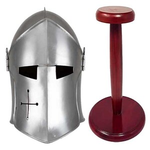 May include: A silver helmet with a cross on the front, displayed on a wooden stand with a red finish.