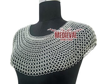 May include: A silver chainmail coif, displayed on a black mannequin. The coif is made of small, interlocking metal rings, designed to protect the neck and shoulders. The text "MEDIEVAL ARMS SHOP" is visible.