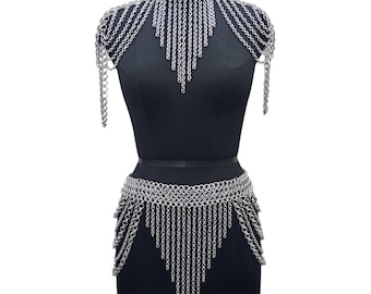 May include: A silver chainmail necklace and matching skirt with a fringe design. The necklace is worn on a black mannequin.