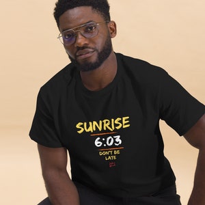 May include: Black t-shirt with a yellow graphic that says "Sunrise 6:03 Don't be late".