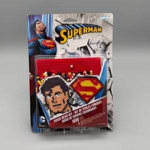 May include: A Superman fused bead kit in original packaging featuring a graphic of the character. The kit includes 1000 beads, a red pegboard, and a pattern sheet to create a pixelated Superman face and the iconic red and yellow S-shield logo.