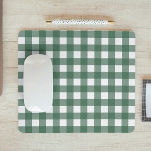 May include: A green and white checkered mouse pad with a white wireless mouse on top. The mouse pad is on a light wood surface.