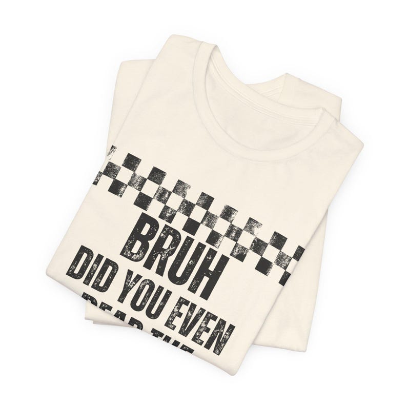 May include: Cream-coloured t-shirt with a black and white chequered design across the top. The shirt features the phrase "BRUH DID YOU EVEN" in bold, distressed black lettering. The shirt is folded neatly.