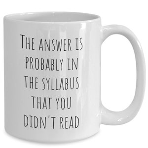 Puede incluir: Taza de caf&eacute; de cer&aacute;mica blanca con texto negro que dice "La respuesta probablemente est&aacute; en el temario que no le&iacute;ste."
