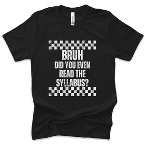 May include: Black t-shirt featuring the white text "BRUH DID YOU EVEN READ THE SYLLABUS?" with a checkered pattern above and below. The shirt is made of a soft material.