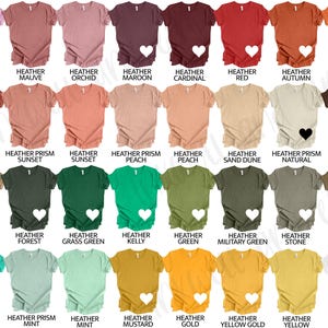 May include: A selection of short-sleeved t-shirts in a range of colours, such as pink, red, green, and yellow. Each shirt features a heart graphic and a colour name printed underneath. The shirts are shown against a white backdrop.