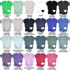 May include: A selection of short-sleeved t-shirts in a range of colours, including green, blue, and pink. Each shirt has a white heart graphic. The shirts are labelled with colour names such as "Kelly," "Mint," and "Heather."