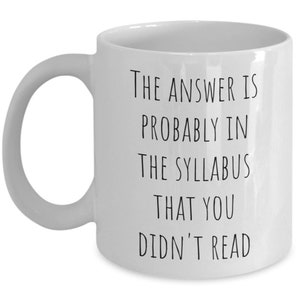 Puede incluir: Taza de caf&eacute; de cer&aacute;mica blanca con texto negro que dice "La respuesta probablemente est&aacute; en el temario que no le&iacute;ste".