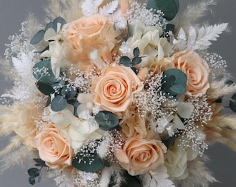 Bridal bouquet of dried flowers in peach, apricot, cream and white with stabilized roses
