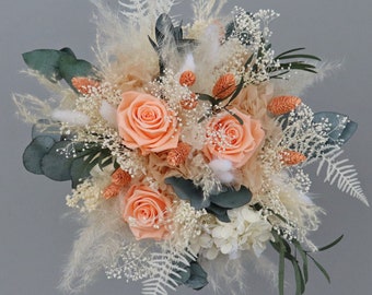 Bridal bouquet of dried flowers in shades of orange, cream and peach with stabilized roses