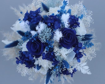 A delicate bridal bouquet of dried flowers in shades of blue, cream and white with preserved roses.
