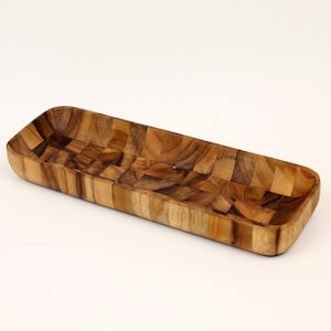Könnte beinhalten: Ein langes, rechteckiges Holztablett mit einem Schachbrettmuster. Das Tablett ist aus hellem und dunklem braunem Holz gefertigt.