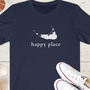 May include: A navy blue t-shirt with a white outline of an island and the text "happy place".