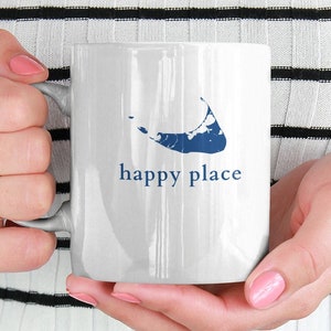May include: White ceramic mug with a blue outline of an island and the text "happy place".