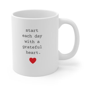May include: White ceramic mug with black text that reads "start each day with a grateful heart." A red heart is below the text.