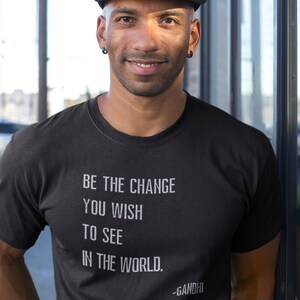 May include: A black t-shirt with white text that reads "Be the change you wish to see in the world. -Gandhi".