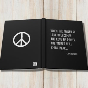 May include: A black book with a white peace sign on the left page and a quote by Jimi Hendrix on the right page. The quote reads: "When the power of love overcomes the love of power, the world will know peace."
