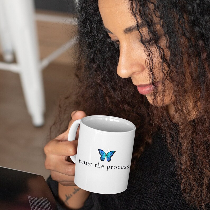 May include: White ceramic mug with a blue butterfly graphic and the text "trust the process".