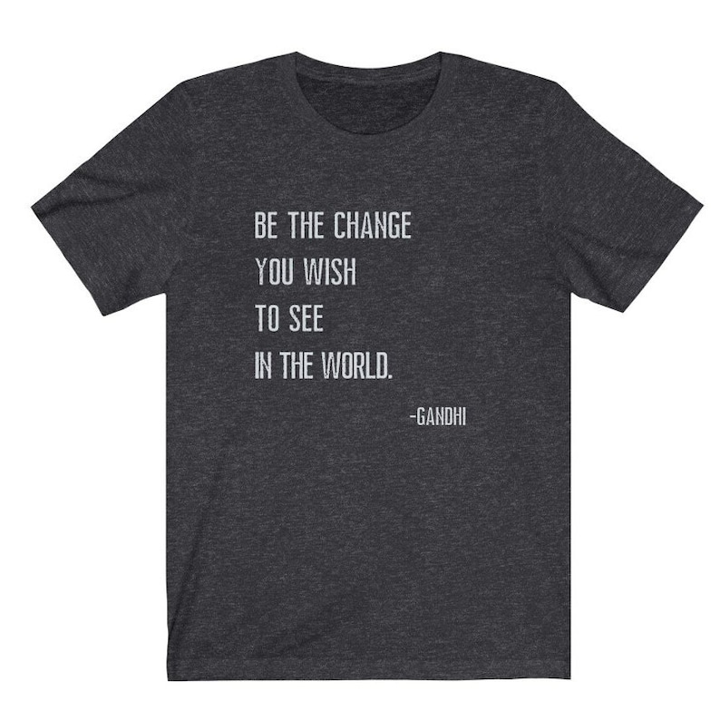 May include: Dark heather grey t-shirt with a white quote that reads "Be the change you wish to see in the world. -Gandhi".
