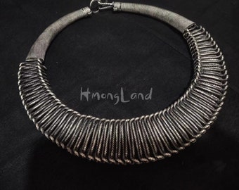 May include: A silver necklace featuring a distinctive design of woven metal strands. The necklace is open at the back and has a clasp fastening.