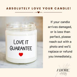 以下が含まれることがあります： 「LOVE IT GUARANTEE」と赤いハートの白いラベルが付いた透明なガラス瓶のキャンドル。上部には「ABSOLUTELY LOVE YOUR CANDLE!」の文字。背景は明るいベージュです。