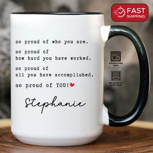 May include: White ceramic mug with a black handle and rim. The mug features the text "so proud of who you are" and "Stephanie" in a handwritten font. The mug is dishwasher and microwave safe.