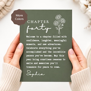 May include: A dark olive green hardcover book with white text that reads CHAPTER forty and a line drawing of daisies. The text continues with a message about celebrating accomplishments and new adventures, ending with the name Sophia.