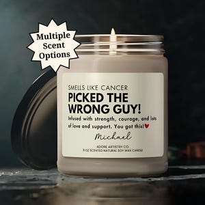 May include: A brown soy wax candle with a white label that reads "Smells Like Cancer Picked the Wrong Guy!"  Infused with strength, courage, and lots of love and support. You got this!  Michael.  Adore Artistry Co. 9 oz Scented Natural Soy Wax Candle."