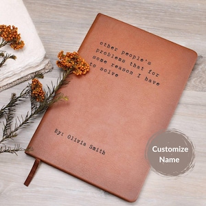May include: A brown leather journal with the quote "other people's problems that for some reason I have to solve" printed on the cover. The journal also has the text "By: Olivia Smith" and a brown ribbon bookmark.
