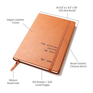 May include: A brown vegan leather journal with a ribbon bookmark and an elastic closure band. The journal is 5.8 inches wide by 8.5 inches long and 5/8 inches thick. It has 100 sheets of lined paper, which equals 200 pages. The journal has the text "the stories inside my head by: jake" printed on the front cover.