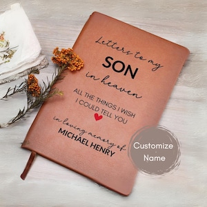 May include: A brown leather journal with the text "Letters to my SON in heaven" and "in loving memory of MICHAEL HENRY". A red heart graphic is included. The journal has a ribbon bookmark.