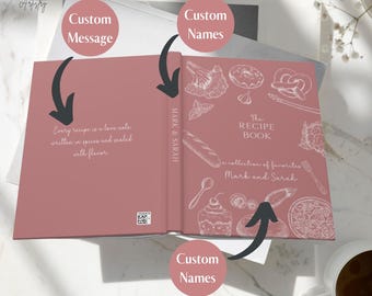 May include: A pink recipe book with a white design of food illustrations and the text "The Recipe Book - A collection of favorites Mark and Sarah". The book has a blank spine for personalization.