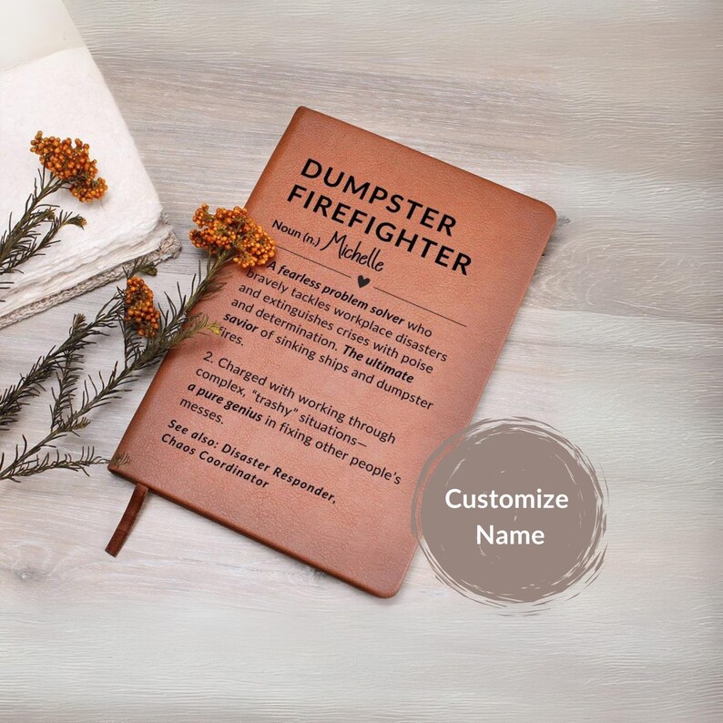 May include: A brown leather-bound notebook with the words "DUMPSTER FIREFIGHTER" in black. The notebook includes a definition and the name "Michelle". A customizable name option is also visible.